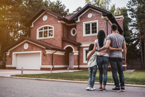 Back view of happy family is standing near their modern house and hugging by huron mortgage, huronmortgages.ca